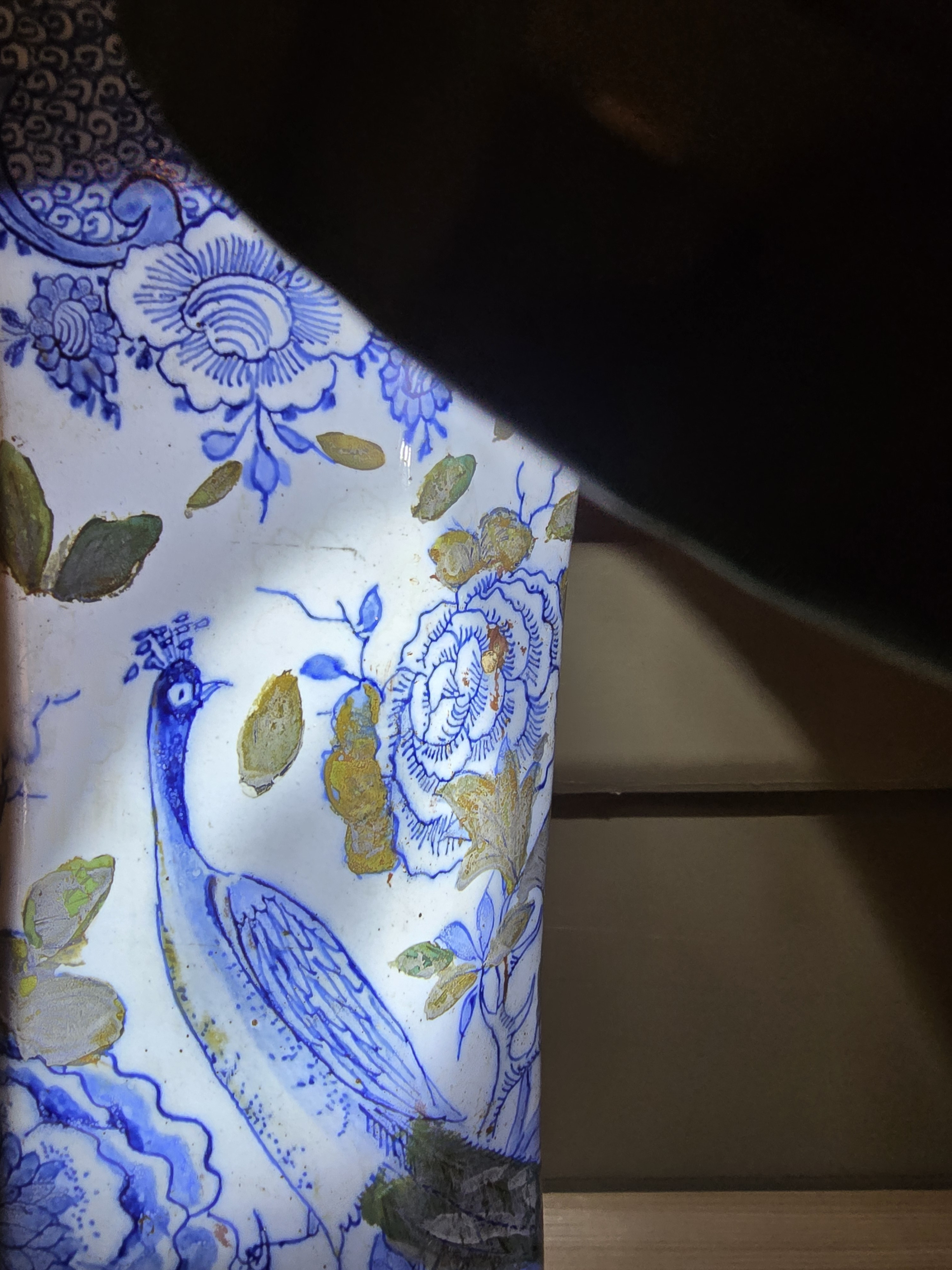 Hier zijn nog net sporen van bloemen en bladeren te zien aan weerszijden van de kop van de pauw.