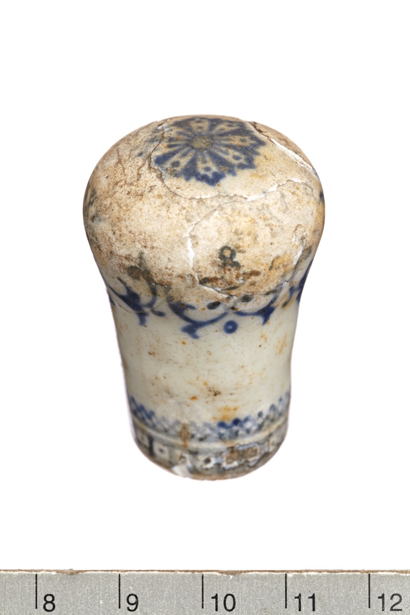 Photo. The knob is worn, coloured white with a blue pattern around